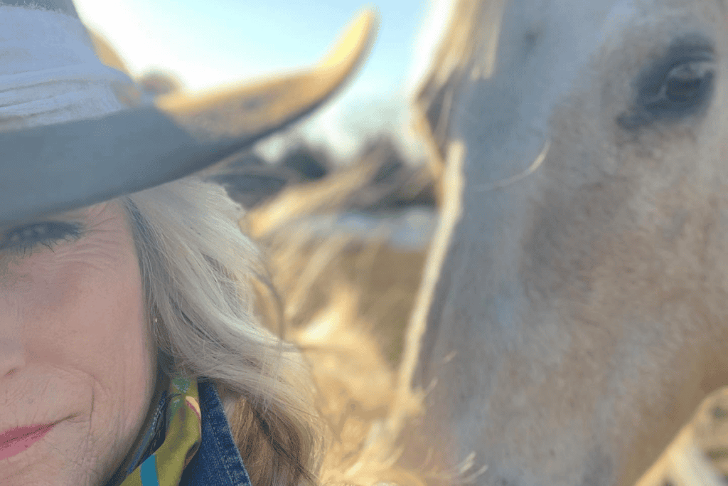 Hatmaker wearing custom western hat next to horse