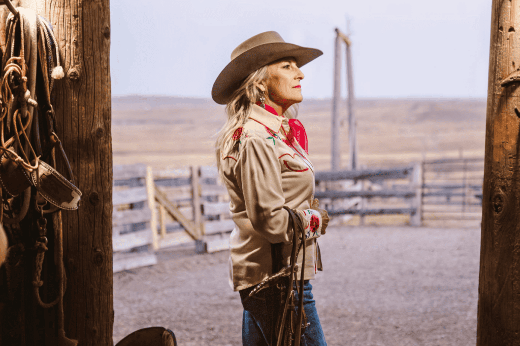 woman wearing custom western hat standing in stable doorway